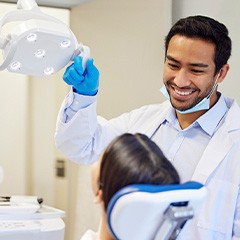 Dentist pulling light closer to examine patient’s mouth