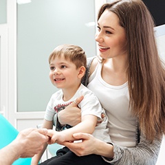 Woman holding child in dental chair