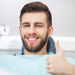 Man in dentist’s chair giving thumbs up