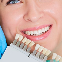 Woman's smile compared with tooth color chart