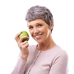 Woman with short hair smiling while holding a green apple