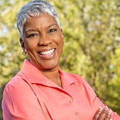 Woman with short hair smiling in pink shirt while standing outside