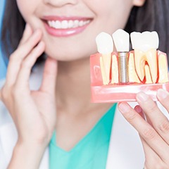 dentist holding a model of a dental implant