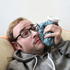 man holding a cold compress to his cheek