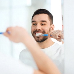 man brushing his teeth in front of a mirror