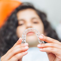 a teen at the dental office holding Invisalign aligners