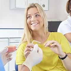 Woman in dental office holding clear aligner
