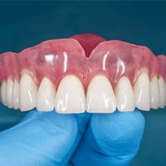 Gloved hand holding dentures in Sunnyvale, TX