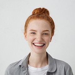 young woman smiling against gray background 