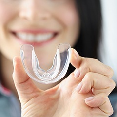 young woman holding up clear mouthguard