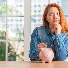 Woman putting coin in piggy bank for cost of veneers in Sunnyvale