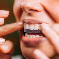 A smiling woman using teeth whitening strips 