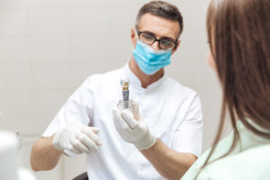 Dentist showing patient dental implant model