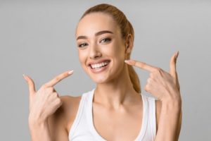 Woman confidently smiling while pointing to her teeth