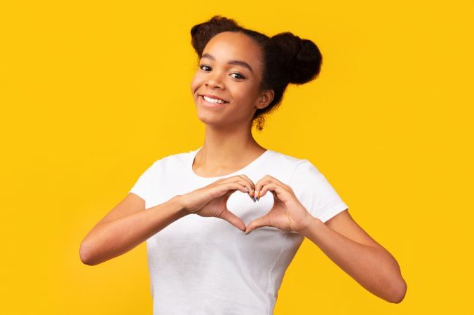 person smiling and making heart with fingers