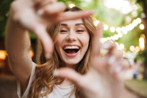 Woman framing her face with her fingers and smiling for the camera