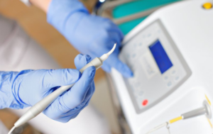 Dentist holding a dental laser while pushing a button on the machine