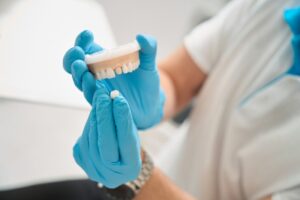 Dentist holding mouth mold and dental crown.