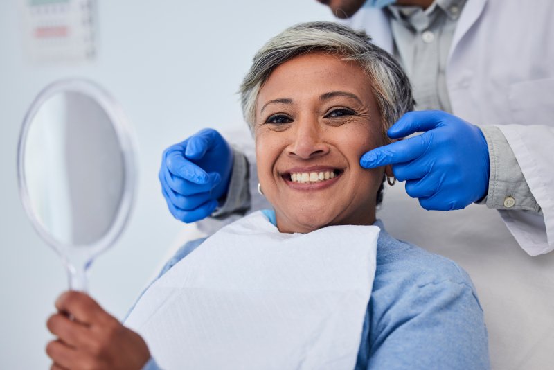 Patient checking teeth in mirror after getting veneers